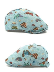 Detail of light blue flat cap featuring colorful butterfly jacquard and side metal buckle