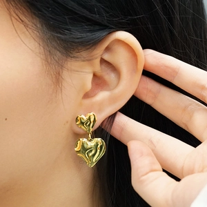 Détail de boucles d'oreilles double cœur en or 18 carats avec texture de métal fondu