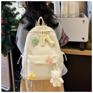 Detailed back view of cream canvas backpack featuring plush star and bear charms