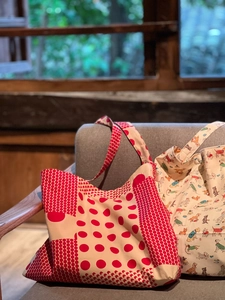 Détail de cabas en toile à pois rouges et imprimé chien posés sur un canapé en tissu