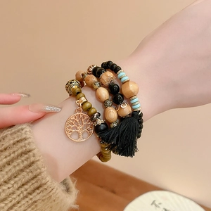 Detail of bohemian multilayer sandalwood beaded bracelet with tree of life charm and tassel