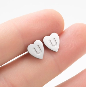 Détail d'une mini boucle d'oreille cœur en argent avec la lettre U gravée