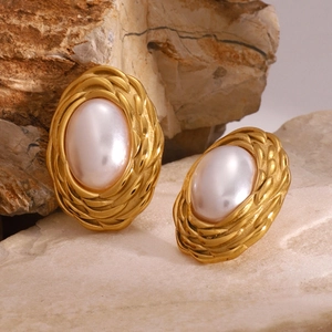 Macro detail of retro pearl stud earrings with golden woven texture on a natural stone