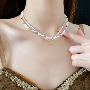 Detail of double-layer faux pearl and colorful stone necklace with golden droplet pendant