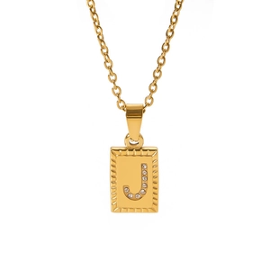Macro view of gold rectangle pendant with cubic zirconia letter J and radial texture