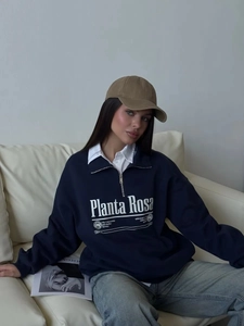 Navy blue oversized half-zip sweatshirt with white logo print on leather sofa