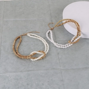 Detailed macro view of layered white faux pearls and golden beads necklace with clasp
