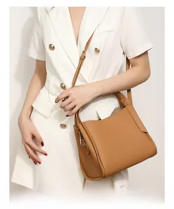 Detail of caramel lychee grain leather bucket bag with top handle and slim shoulder strap