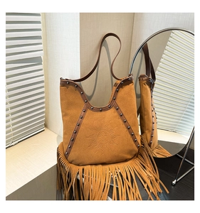 Detail of brown suede tote with sun embossed pattern, metal rivets and long tassels