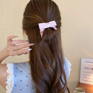 Detail of pink satin bow hair tie on a half-up hairstyle for a sweet feminine look
