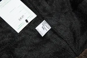 Macro shot of black plush lining and 100% polyester care label for long wool coat