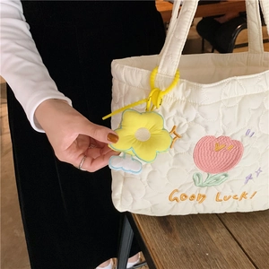 Detailed embroidery of pink tulip and yellow Good Luck text on white quilted tote bag