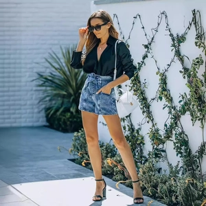 Pantaloncini di jeans blu a vita alta con cintura e camicia in raso nero stile alla moda