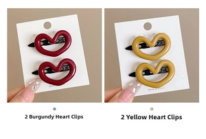 Detailed view of wine red and mustard yellow heart hair clips on white card packaging