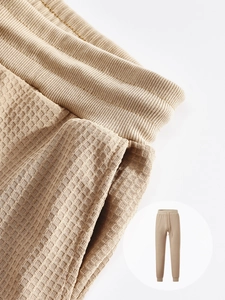 Macro detail of men's khaki waffle knit joggers showing elastic waist and fabric texture
