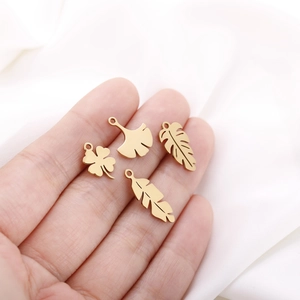 Close-up of golden hollow leaf pendants including ginkgo and clover for DIY jewelry