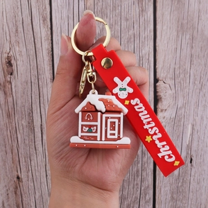 Detail of gingerbread house PVC keychain with red silicone strap held in hand