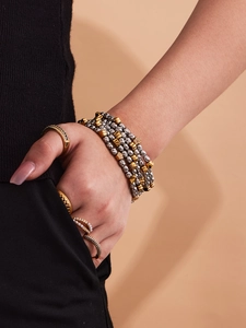 Detail of beaded bracelet and stacked gold rings with zircon and pearls on model