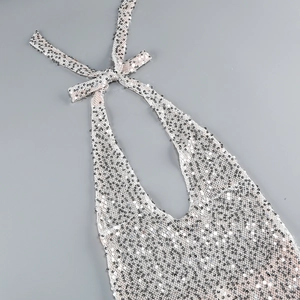 Detail of silver sequin halter neck tie and shimmering fabric on backless evening dress