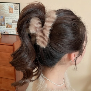 Détail de la pince à cheveux en peluche rayée montrant la fixation dans un décor minimaliste