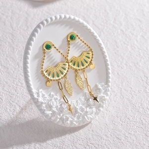 Detail showing vintage gold fringe earrings with green stones and star-shaped charms