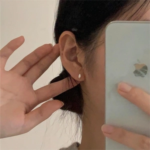 Minimalist silver oval teardrop stud earrings worn in an aesthetic mirror selfie