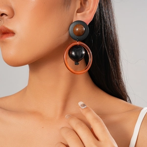 Boucles d'oreilles rétro avec bois brun et résine orange portées par un mannequin