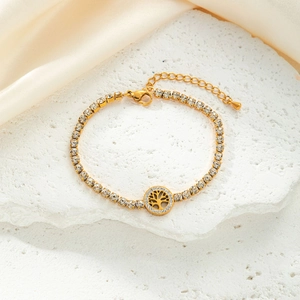 Close-up of golden Tree of Life bracelet with white rhinestones on marble stone surface