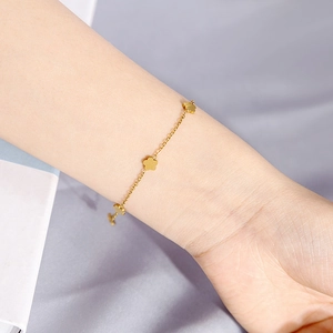 Delicate gold link bracelet with small flower charms worn on a wrist for elegant styling
