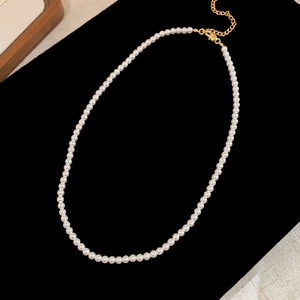 Detailed close-up of a vintage pearl necklace with golden clasp on black velvet background