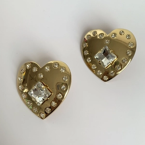 Macro shot of gold heart-shaped earrings featuring a large diamond and crystal halo detail