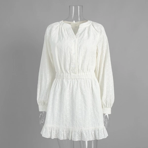 Détail de la robe blanche à col en V avec broderie, taille élastique et ourlet à volants
