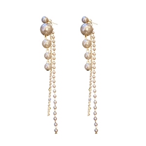 Golden tassel earrings with grey pearls and sparkling zircons in a studio setting