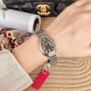Close-up of a silver snake-shaped luxury watch with a black dial on a woman's wrist