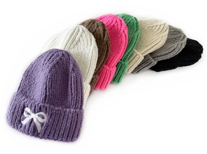 Detail view of colorful winter knit hats for kids with delicate bow embroidery in 8 colors