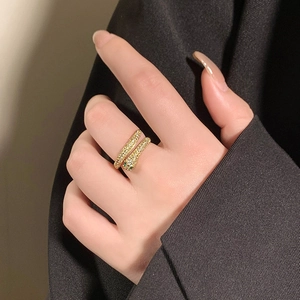 Close-up of a gold-plated snake ring with sparkling zircons and green gem eyes on finger