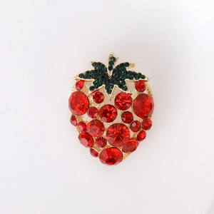 Close-up of strawberry brooch with red crystals and green rhinestones on gold base