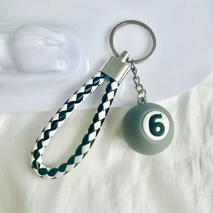 Detail of grey mini billiard ball number 6 keychain with black and white braided leather