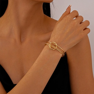 Detailed view of golden triple-layered geometric cuff bracelet on a female model