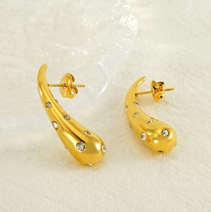 Detailed close-up of 18K gold teardrop earrings with crystals on white fabric