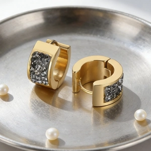 Detail of gold-plated stainless steel earrings with dark grey sparkling stone inlay