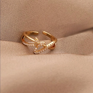 Close-up of golden butterfly open ring with sparkling crystal accents on fabric