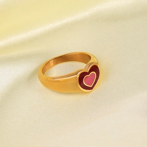 Close-up of golden 18K gold-plated ring with a red heart design on soft fabric