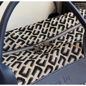 Gros plan d'un sac de voyage bleu marine avec motif monogramme géométrique et détail zippé