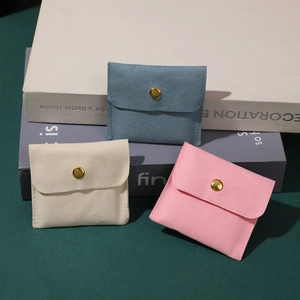 Microfiber jewelry snap pouches in blue, cream, and pink with golden metal buttons