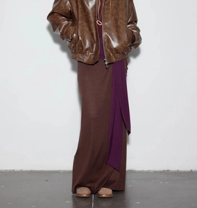 Detail of color-block knit maxi skirt with purple waist tie and brown aviator jacket