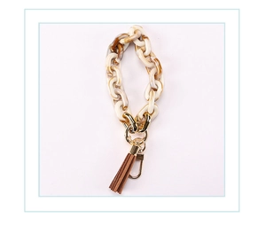 Macro detail of acrylic tortoiseshell chain with leather tassel and gold lobster clasp