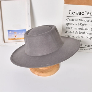 Detail of a grey wool felt flat top wide brim hat on a minimalist wooden stand