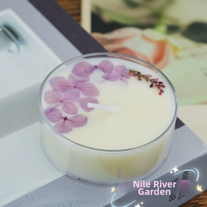 Macro view of a handmade scented candle with purple dried flowers in a glass cup