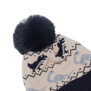 Détail du motif dinosaure en tricot pour enfants avec un pompon bleu en fausse fourrure